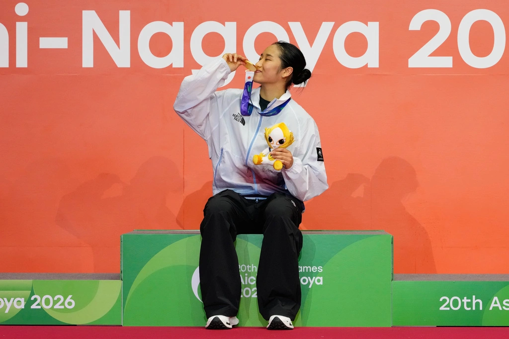 An Se-young of South Korea kisses her gold medal while sitting on the podium at the Asian Games in Ichinomiya